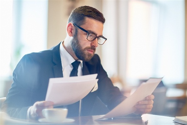 Homem de terno e óculos estudando com papéis